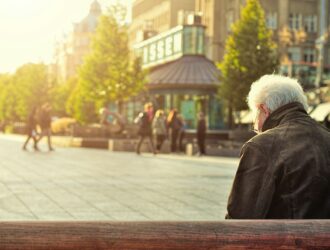 man sitting on brown wooden bench